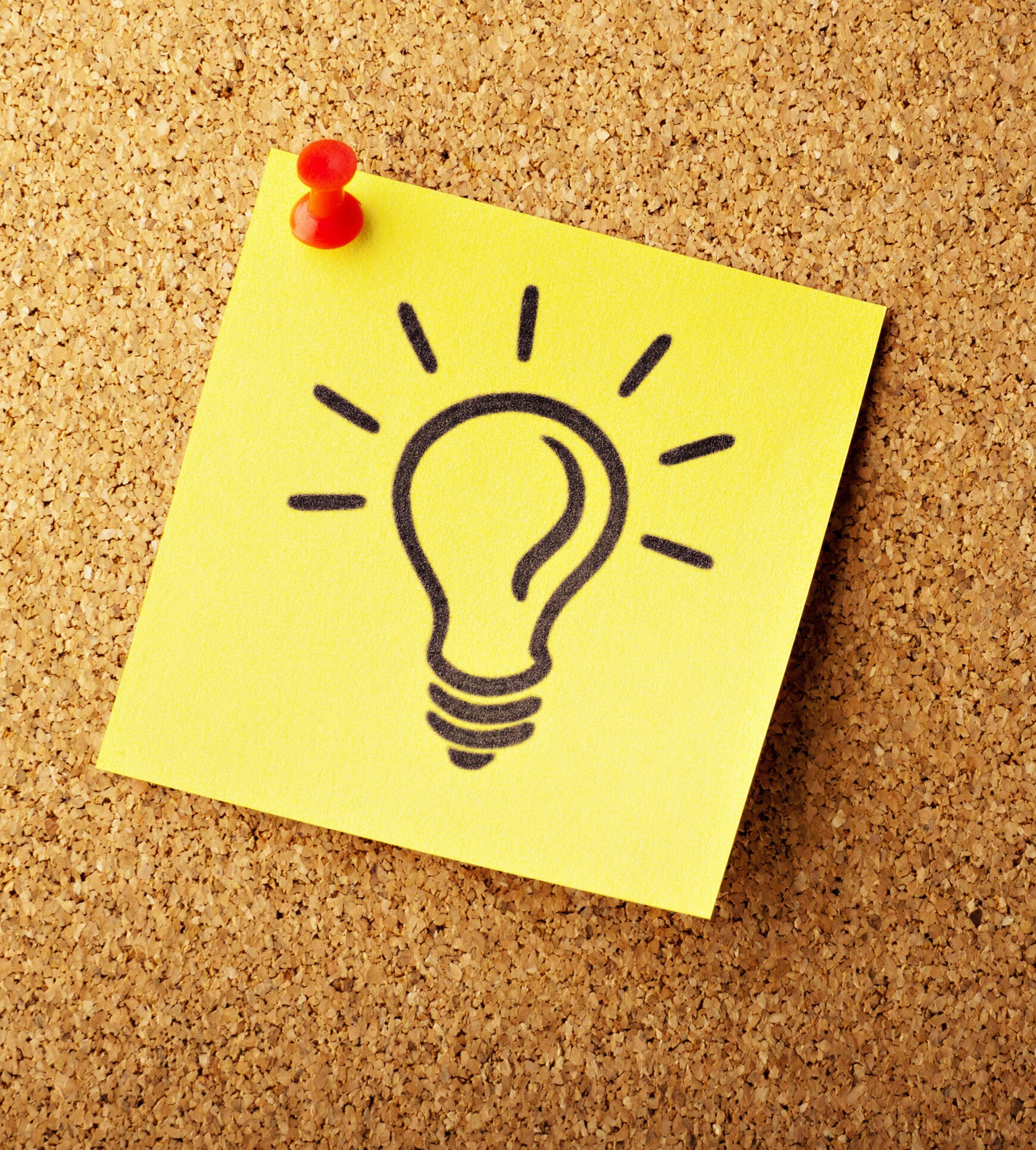 Lightbulb drawn on a sticky note and pinned to a corkboard